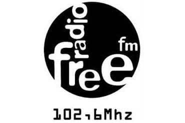 Logo des Radiosenders "Radio free FM". Die Worte in weißer Schrift auf schwarzem runden Untergrund. Darunter der Schriftzug "102,6Mhz".