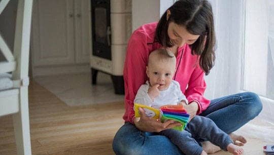 Eine Frau und ein Baby schauen sich ein Fühlbuch an.