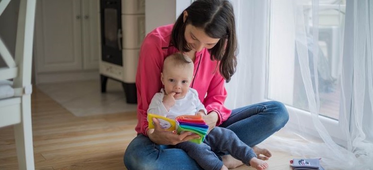 Eine Frau und ein Baby schauen sich ein Fühlbuch an.