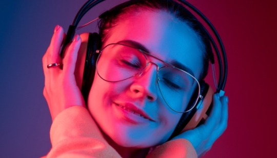 Junge Frau,  die über Kopfhörer Musik hört