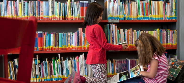 Zwei Kinder beim Lesen von Büchern in der Kinderbibliothek