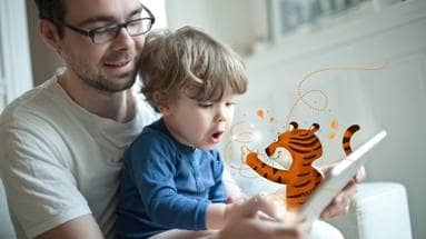 Ein Kind schaut sich mit seinem Papa ein interaktives Kinderbuch mit der App Tigerbooks an
