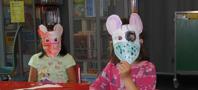 Zwei Kinder mit einer selbst gebastelten Maske